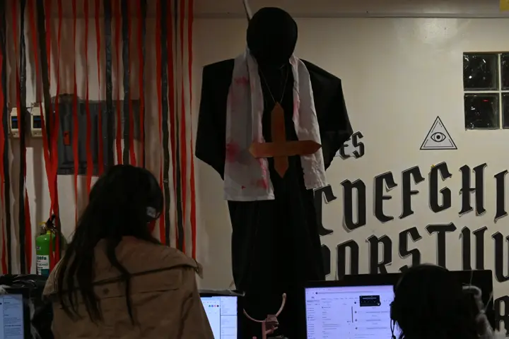 A wall painted as a giant spirit board with a hanging figure above the desks