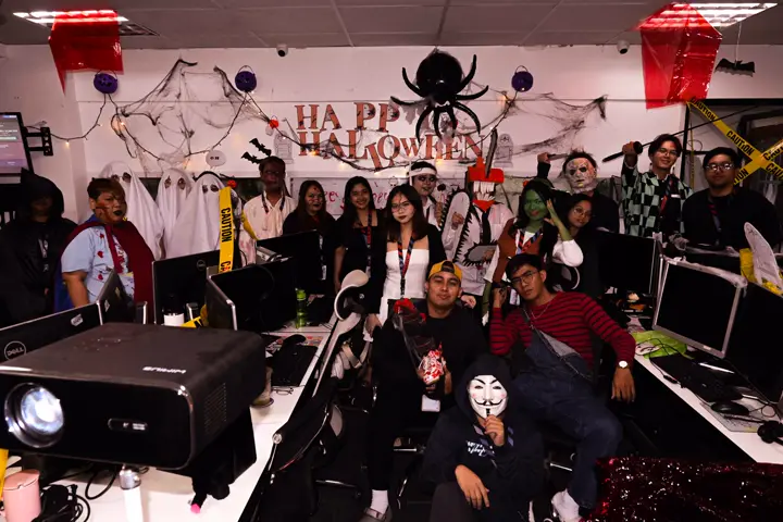 The whole team in costume gathered under a 'Happy Halloween' banner