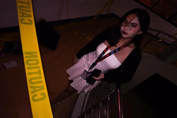 Teammate in a white dress posing on the stairs by caution tape