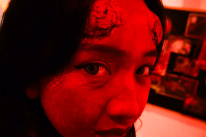 Close-up of a face in blood make-up under red light